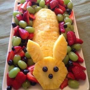 an animal made out of fruit on top of a plate with grapes and strawberries