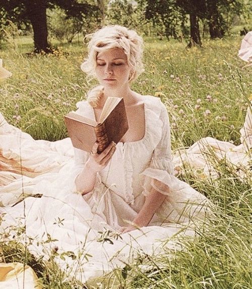 a woman sitting in the grass reading a book