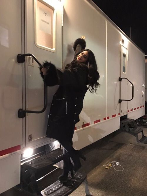 a woman standing on the side of a horse trailer with her hands in the door