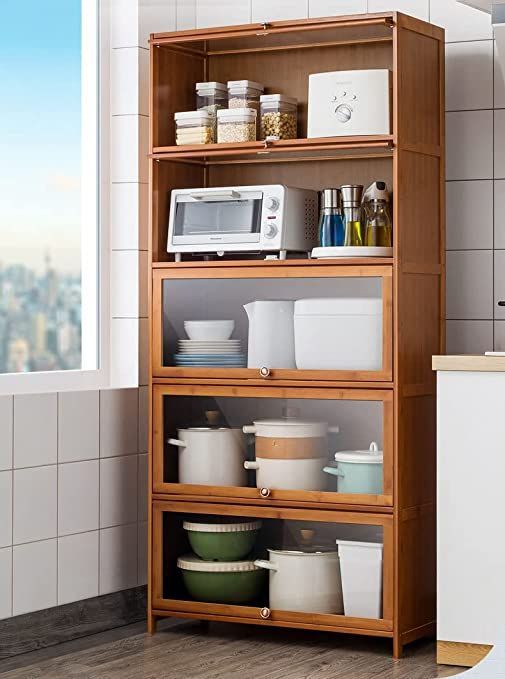 a wooden shelf filled with lots of dishes next to a white microwave oven and window