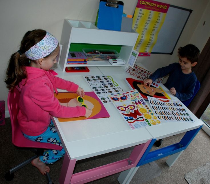 two children are playing at a table with pictures and magnets on the table top