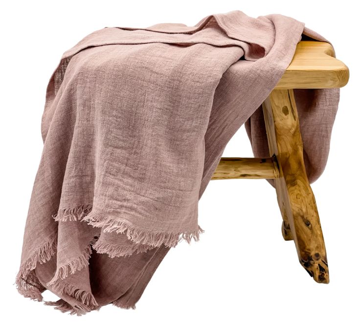 a wooden stool with a pink blanket draped over it