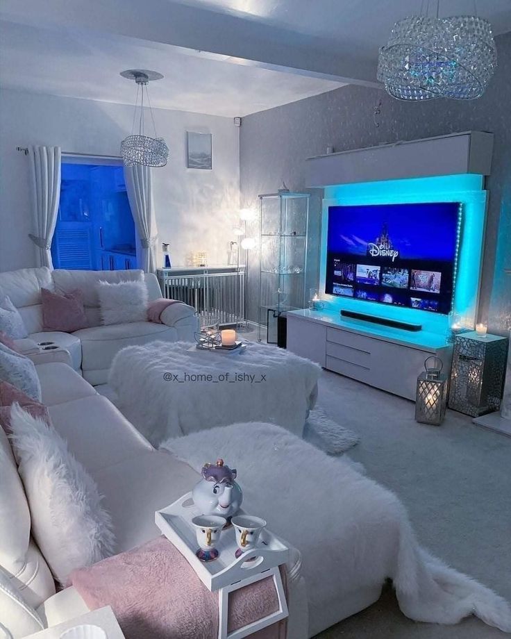 a living room filled with white furniture and a flat screen tv mounted to the wall