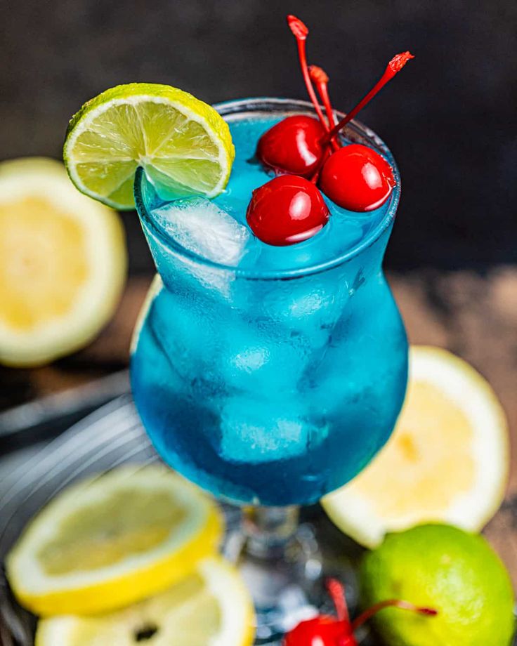 a blue cocktail garnished with cherries and limes