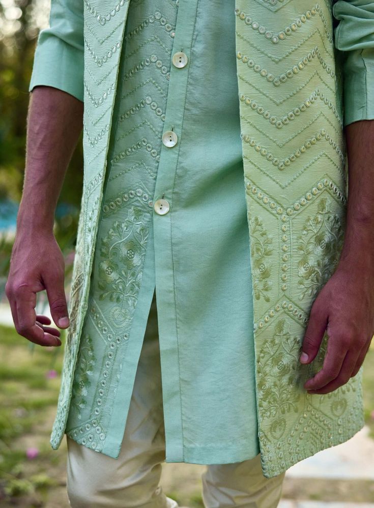 The nehru jacket boasts a sleek silhouette and front-open design, offering a touch of understated elegance. Its mint green hue is soft and refreshing, ideal for festive occasions that call for a light yet striking palette. The matching mint green kurta complements the jacket seamlessly, with a front-open design that adds versatility and comfort. The off-white churidar adds a classic touch, providing a subtle contrast to the mint green ensemble. This combination is perfect for day or evening events, ensuring you look stylish and feel at ease. White Churidar, Nehru Jacket, Nehru Jackets, Bespoke Tailoring, Open Design, Understated Elegance, Churidar, Look Stylish, Cotton Silk