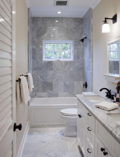 a bathroom with white cabinets and marble counter tops, along with a toilet and tub