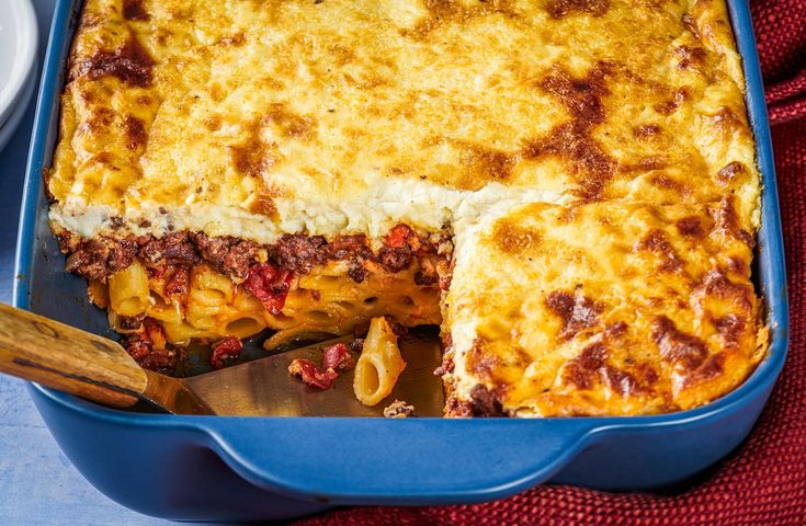 a casserole with meat and cheese in a blue dish on a red cloth