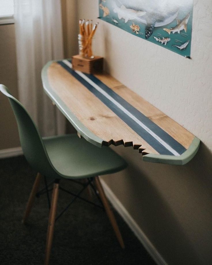 a wooden table sitting next to a green chair in front of a painting on the wall