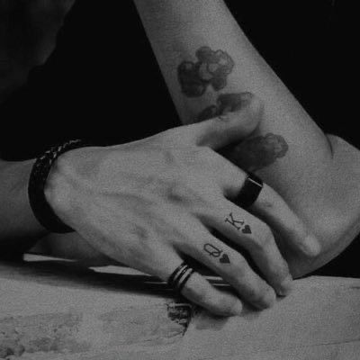 two people holding hands with tattoos on their arms and fingers, both showing the same tattoo