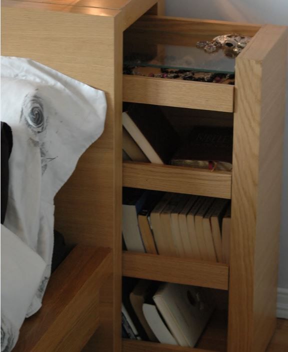 a lamp is sitting on top of a wooden table next to a book shelf with books