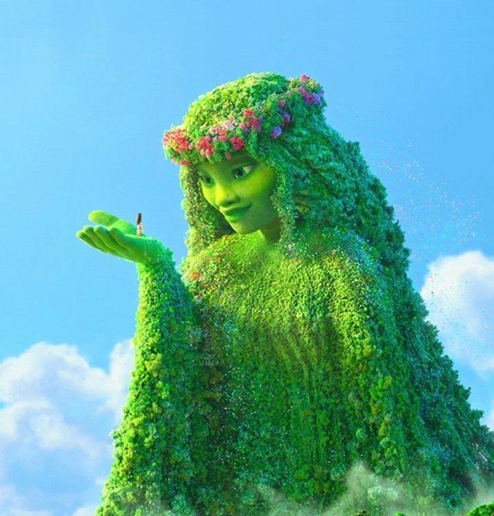 there is a very large green woman in the air with flowers on her head and arms