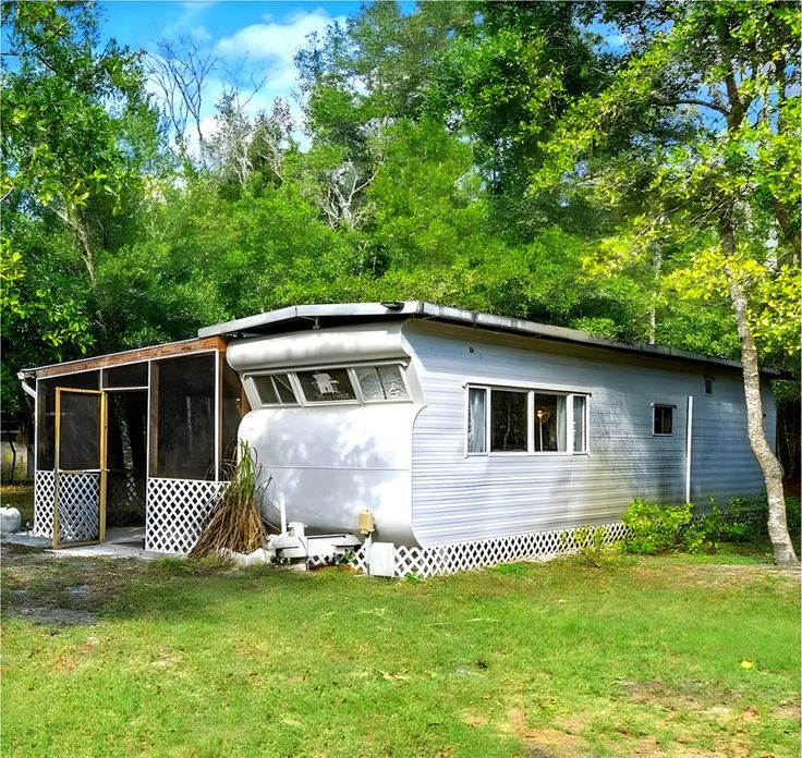 a mobile home sits in the middle of a grassy area with trees and grass around it