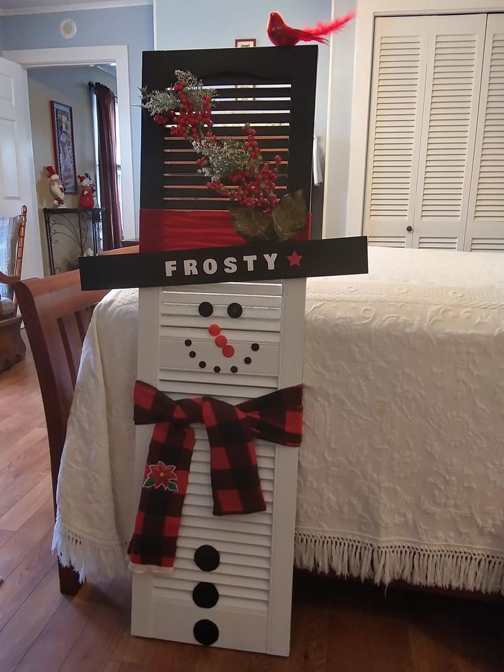 a snowman made out of shutters on top of a bed with red and black decorations