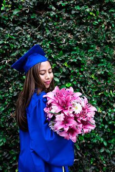 a woman in blue graduation gown holding pink flowers