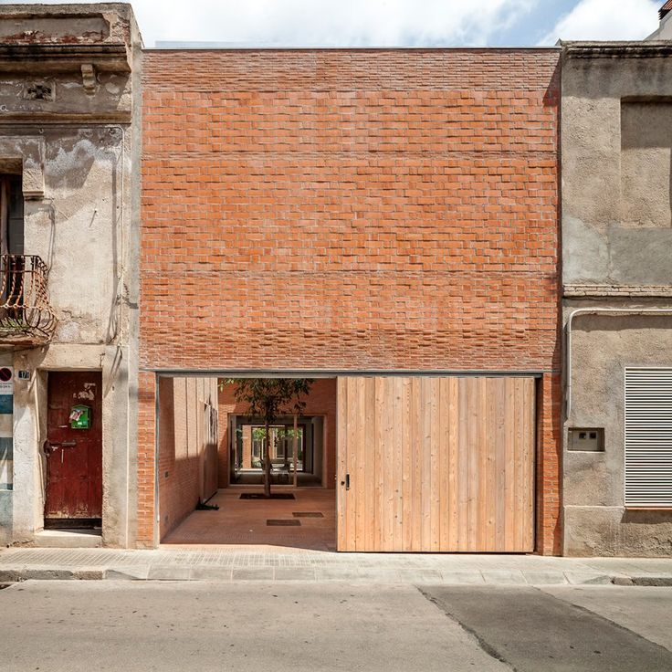 an old brick building with two garages on each side and a wooden door in the middle