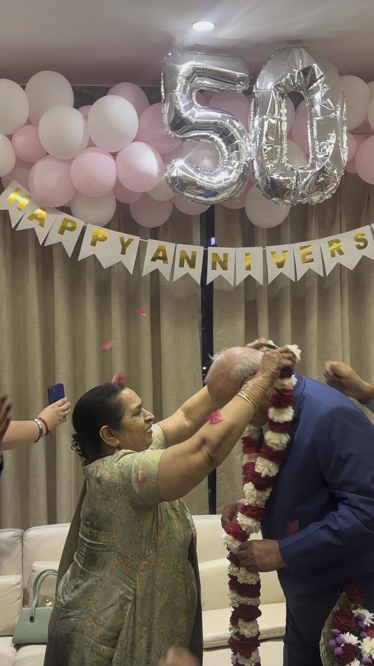 a man and woman standing next to each other in front of balloons on the ceiling