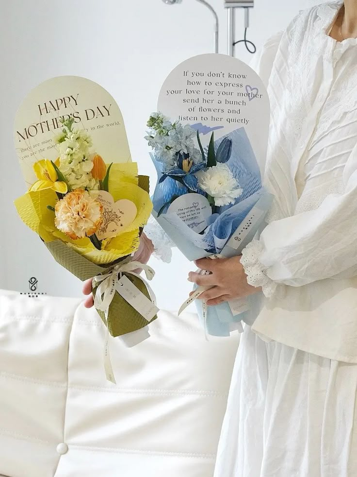 the woman is holding two bouquets of flowers in her hands, and one has a card that says happy mother's day