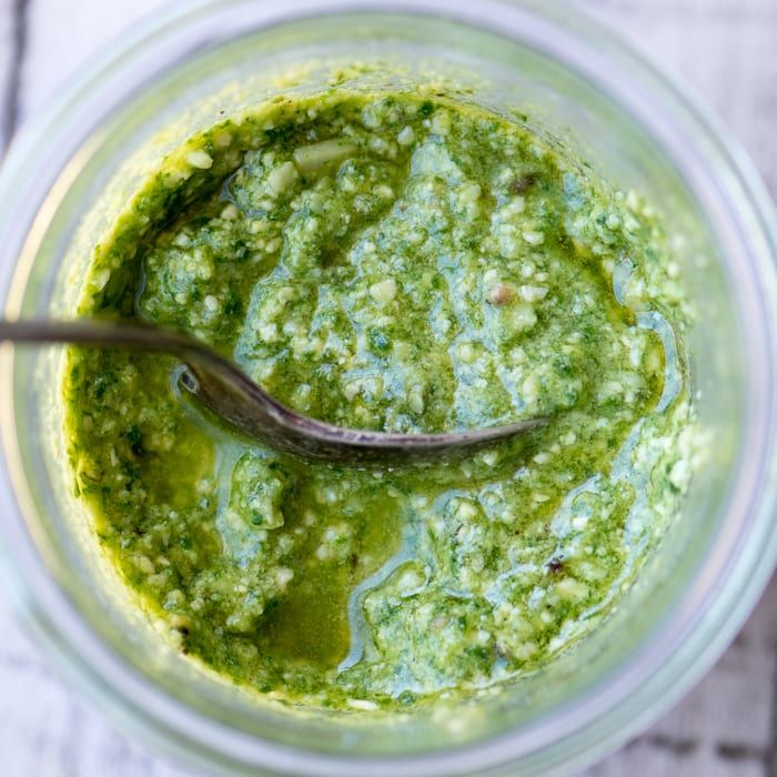 a spoon in a jar filled with pesto