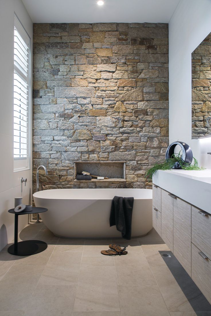 a bathroom with stone wall and white bathtub