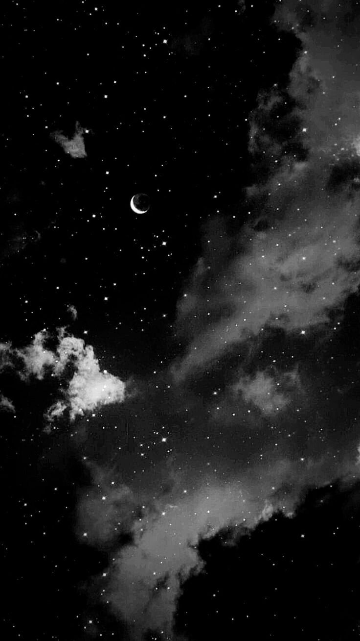 black and white photograph of the night sky with stars, moon and clouds in it