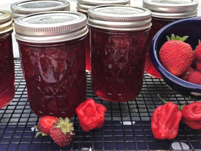 several jars filled with red liquid and strawberries