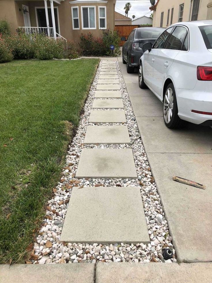 a car parked in front of a house next to a gravel path that has stones on it