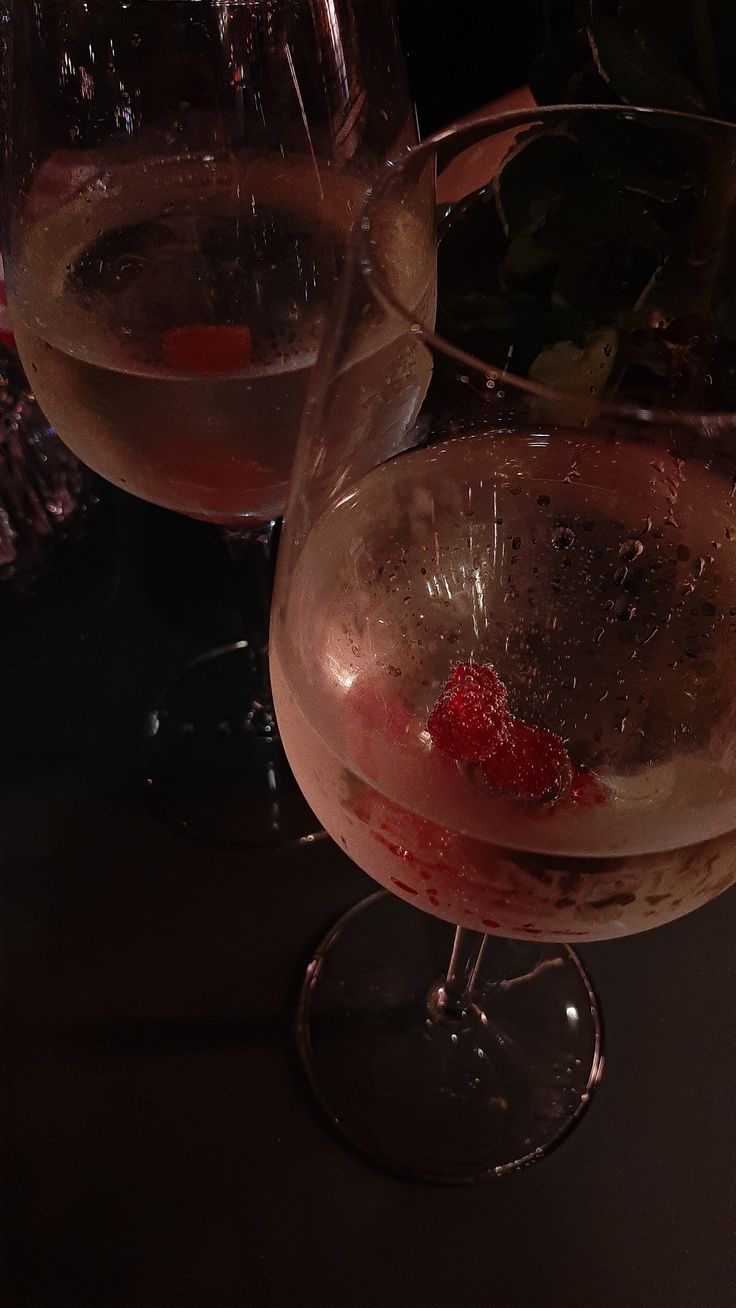 two wine glasses filled with pink liquid and strawberries