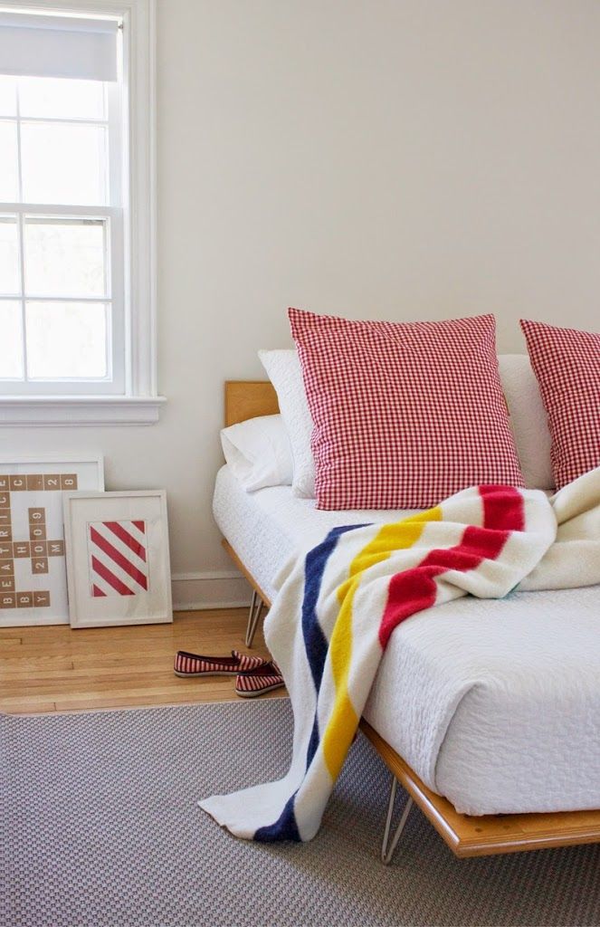 a bed with red, white and blue blankets on top of it next to a window