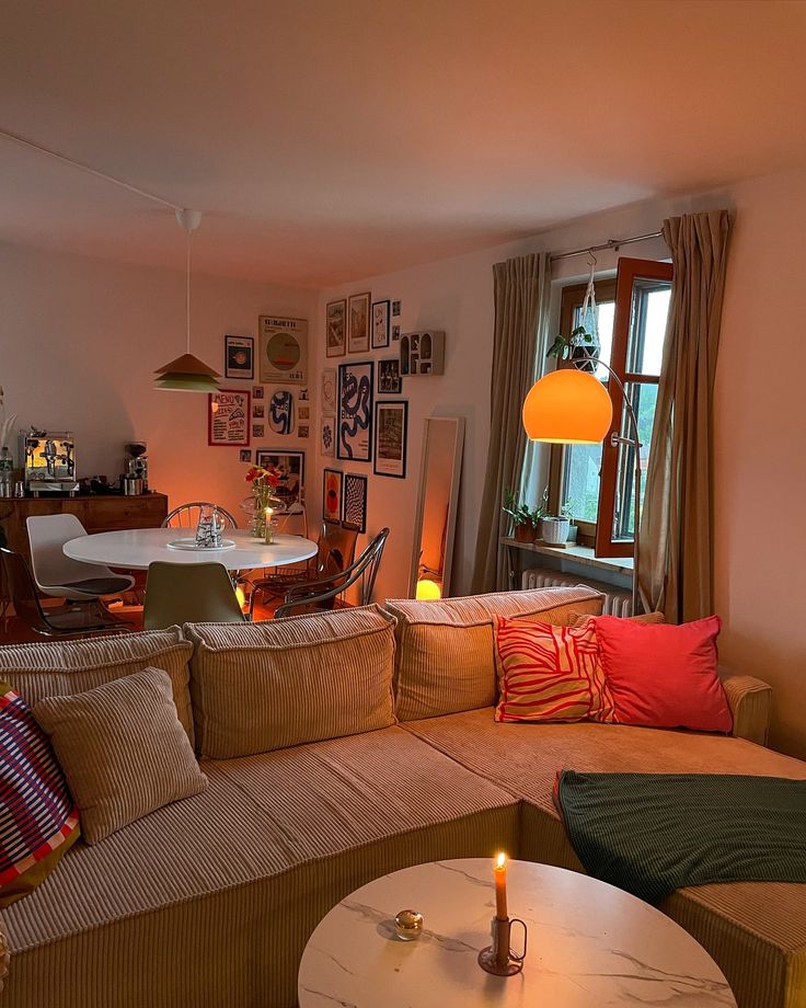 a living room filled with furniture next to a table and window covered in pictures on the wall