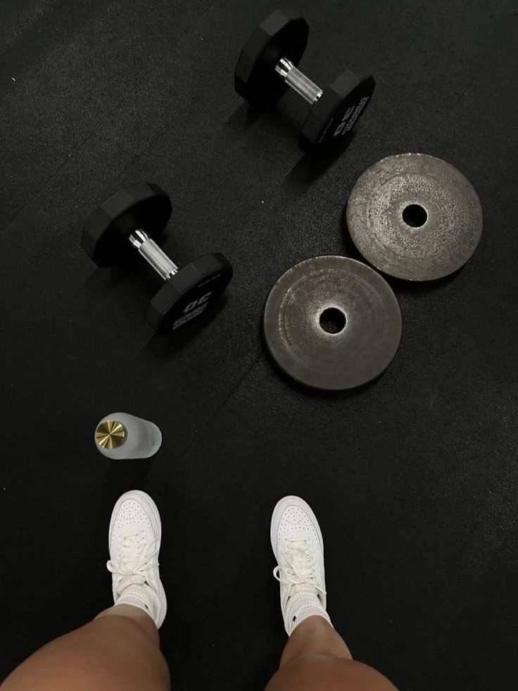 a person standing next to two dumbbells and a pair of shoes