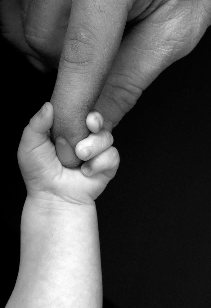 a person holding the hand of a baby's hand with a heart on it