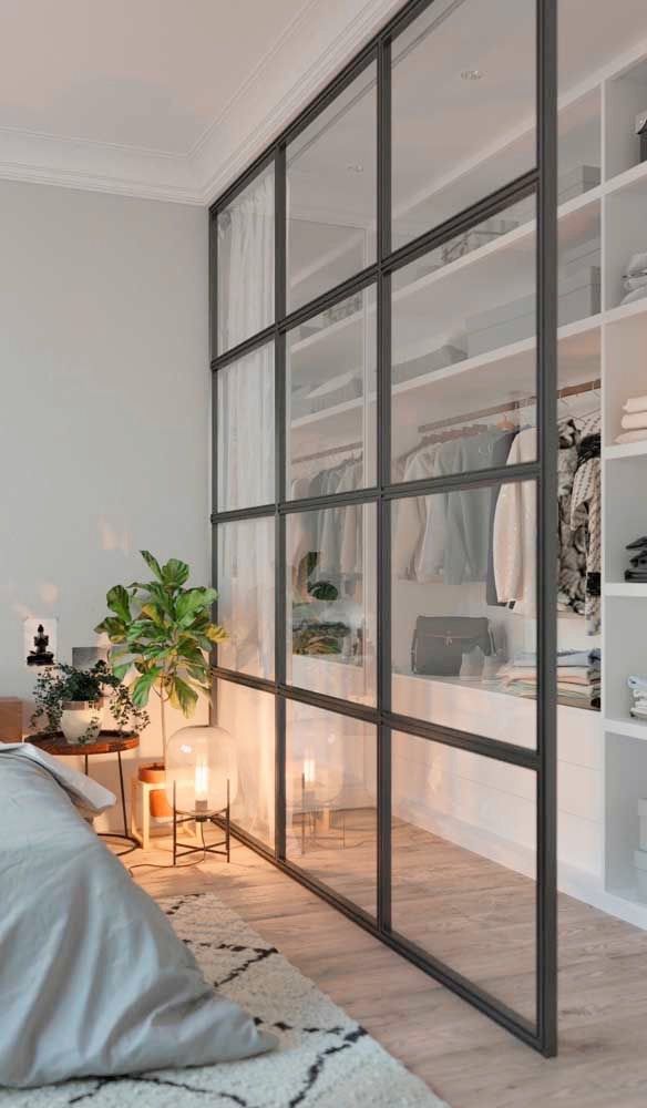 a bedroom with white walls and shelves filled with clothes, plants and candles on the floor