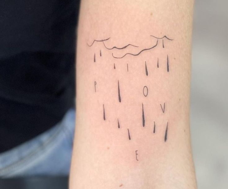 a person with a tattoo on their arm that has rain drops coming out of it