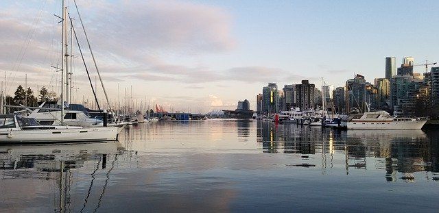 several boats are docked in the harbor with city buildings in the background at sunset or dawn