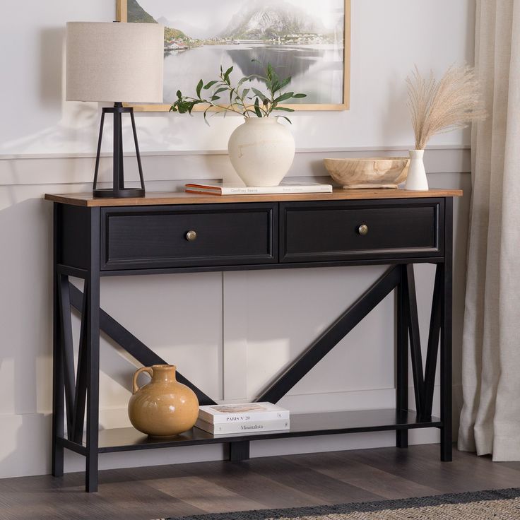 a black console table with two vases on it and a painting hanging over the top