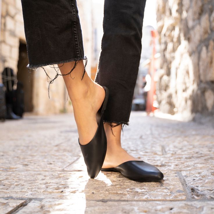 Step into versatile appeal with the Myra mule from Jerusalem Sandals. These leather flats feature a sleek pointed-toe design that elegantly elongates the leg, adding a touch of sophistication to any outfit. The Myra mule is both chic and comfortable, making it the perfect choice for effortlessly pulling together any ensemble. Whether you're dressing up or keeping it casual, this classic and timeless mule is a true wardrobe workhorse. Enjoy the combination of style and comfort with the Myra mule. Sleek Slip-on Mules With Pointed Toe, Modern Black Slip-on Pointed Toe Flats, Sleek Closed Toe Mules With Leather Sole, Sleek Mules With Branded Insole, Sleek Closed Toe Mules With Removable Insole, Chic Mules With Leather Footbed And Almond Toe, Chic Mules With Almond Toe And Leather Footbed, Sleek Mules With Leather Sole For Spring, Sleek Closed Toe Spring Mules