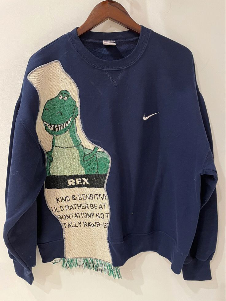 a blue sweatshirt with an image of a dinosaur on it