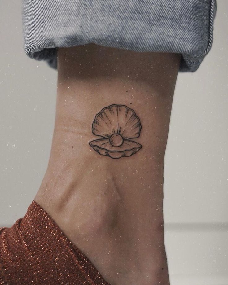 a woman's foot with a small shell tattoo on the side of her ankle