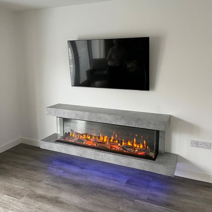 a television mounted on the wall next to a fire place in a room with hardwood floors