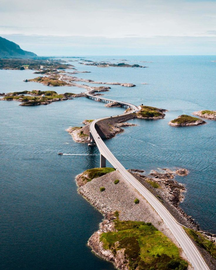 an aerial view of a bridge spanning the width of a large body of water with mountains in the background