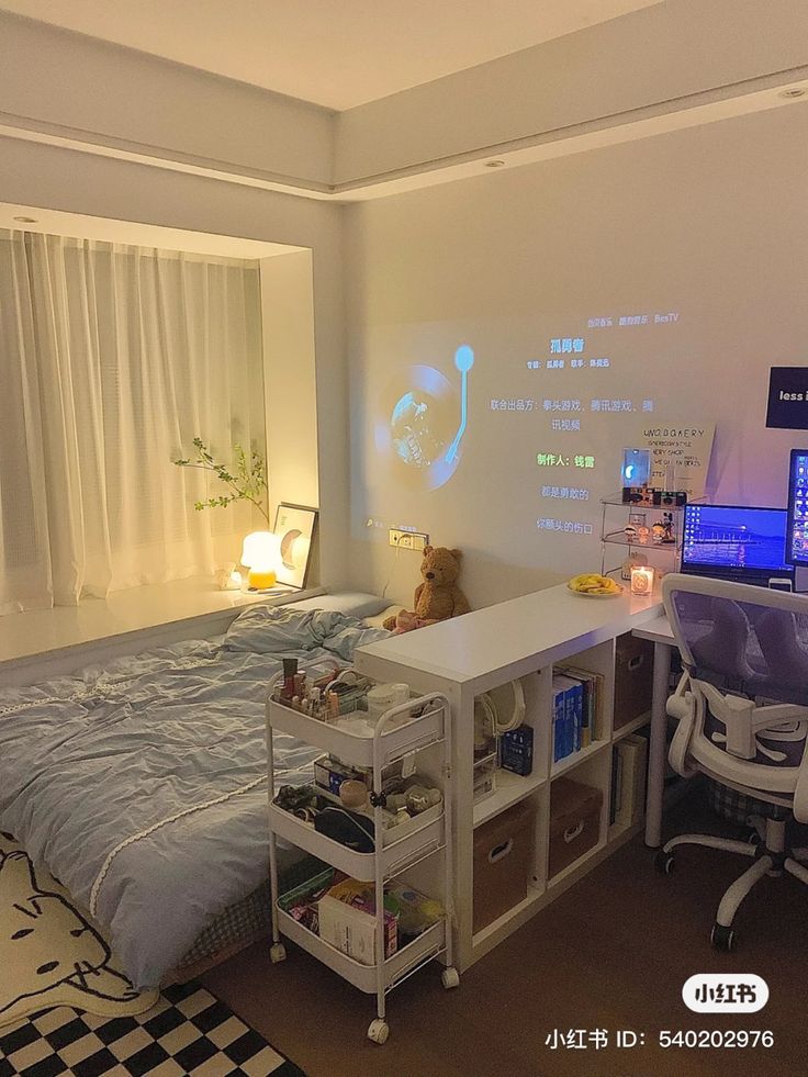 a room with a bed, desk and computer monitor on the wall next to it