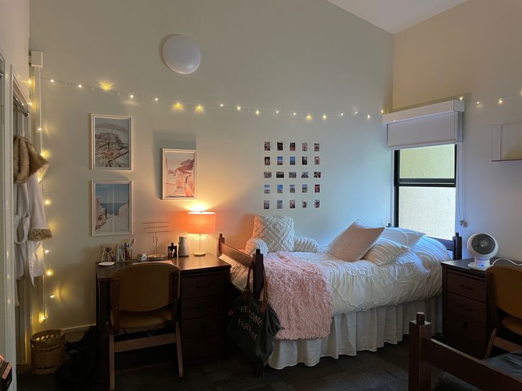 a bed room with a neatly made bed and lights on the wall above it's headboard