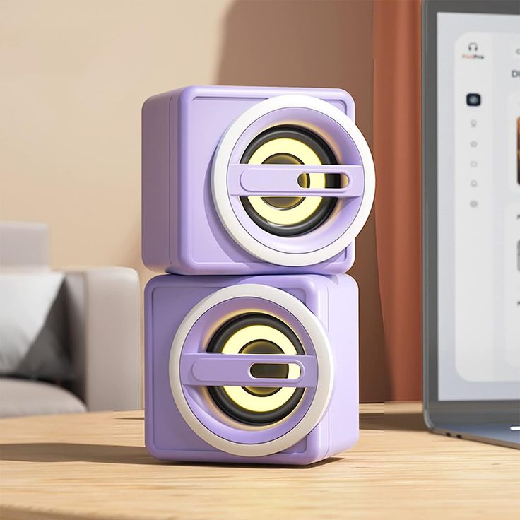 two speakers sitting next to each other on top of a wooden table near a laptop