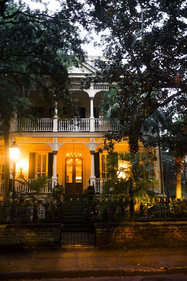 an old house lit up at night with lights shining on the porch and balconies