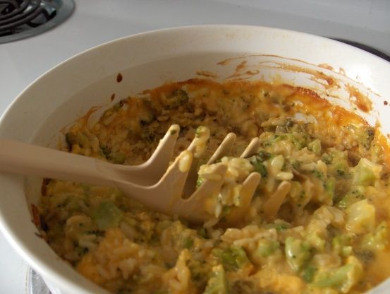 a white bowl filled with food on top of a stove next to a spatula