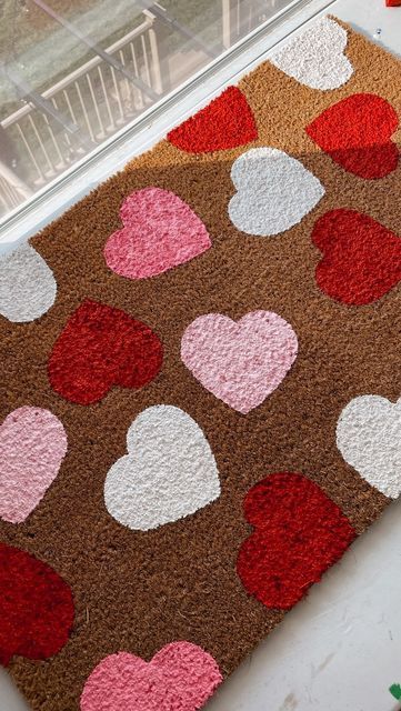 a brown and pink rug with hearts on it next to a window sill filled with flowers