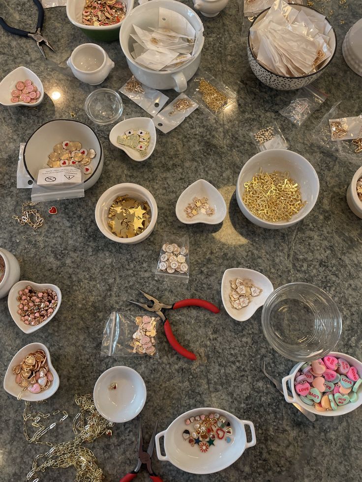 several bowls filled with different types of candies on a marble counter top next to scissors and other items