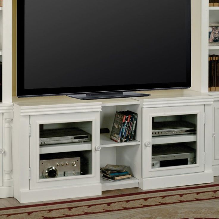 a flat screen tv sitting on top of a white entertainment center next to a book shelf