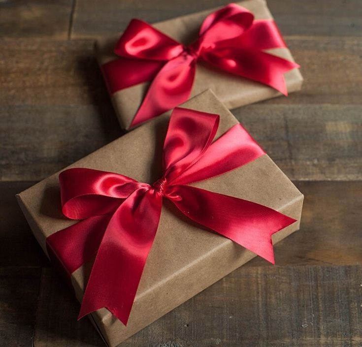 two wrapped gift boxes with red ribbons on them