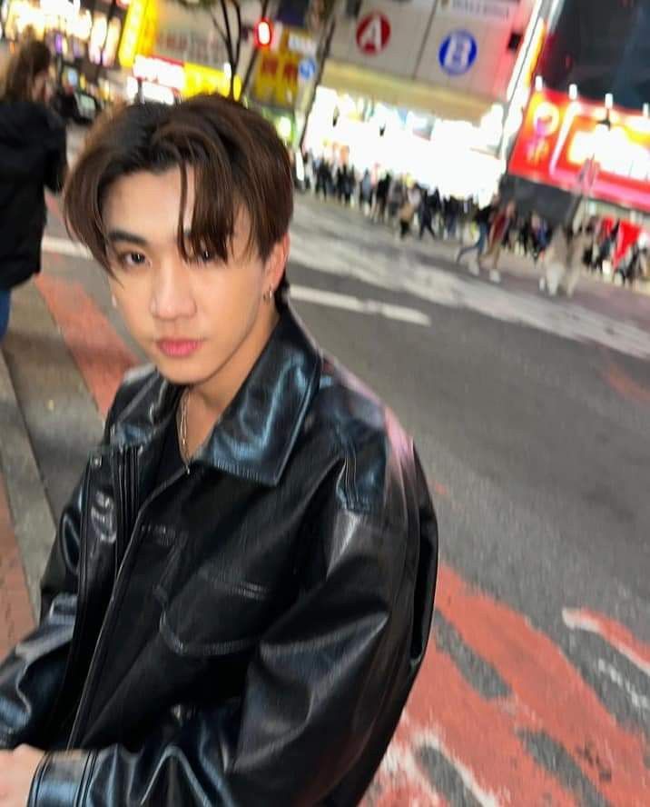 a young man in a black leather jacket on the street